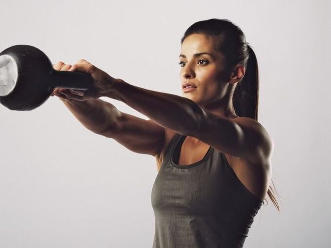 Dívka provádí cvičení na zvětšení prsou pomocí kettlebell